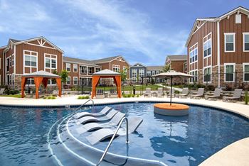an outdoor pool with chairs and umbrellas in front of an apartment building  at Watermark on Twenty Mile, Colorado